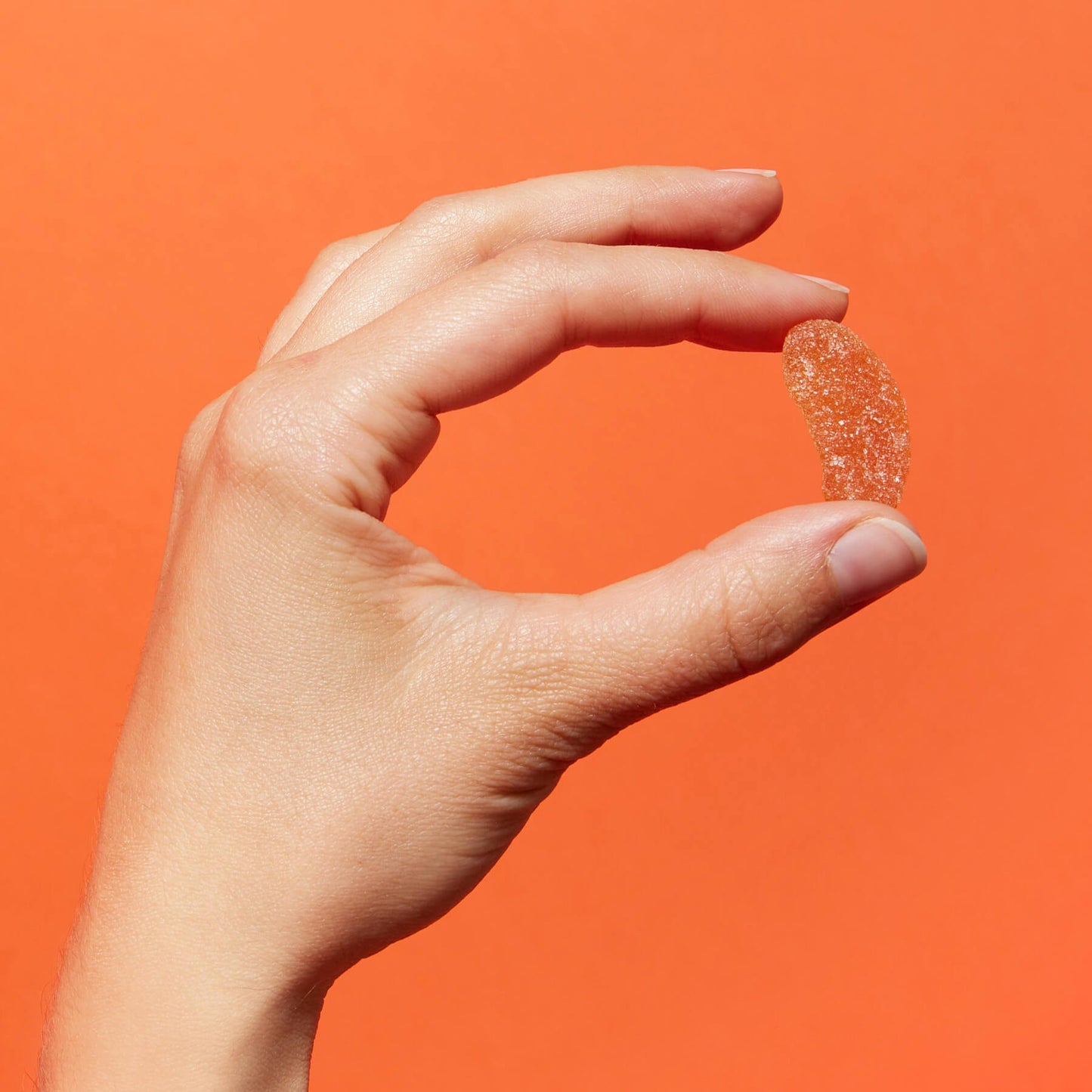 A hand holding a Schiff Vitamins' Airborne Assorted Fruit Gummy