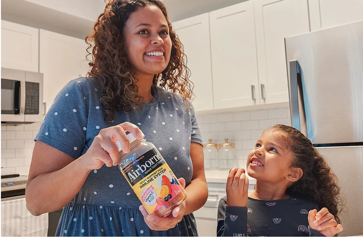 woman and child standing in a kitchen with Airborne product in hand.